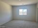 This bedroom features neutral carpet, a window providing natural light, and freshly painted walls, creating a blank canvas at 24627 W Ripple Rd, Buckeye, AZ 85326
