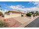 Beige single-story home featuring a spacious driveway, desert landscaping, and a two-car garage at 24907 S Lakestar Dr, Sun Lakes, AZ 85248