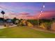 Backyard patio with pavers, a fire pit and outdoor lighting at dusk with mature plantings at 2625 N 24Th St # 22, Mesa, AZ 85213