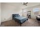 Bright bedroom with neutral walls, carpet flooring, ceiling fan, and two windows providing natural light at 30963 W Columbus Ave, Buckeye, AZ 85396