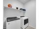 This laundry room features a white washer and dryer with a shelf above at 36085 W Prado St, Maricopa, AZ 85138