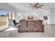 Inviting living room with leather furniture, large sliding glass doors, and an elegant ceiling fan for added comfort at 36085 W Prado St, Maricopa, AZ 85138