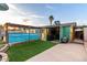 Vibrant backyard featuring artificial turf, colorful sheds, a grilling area, and a cozy covered patio space at 3643 E Friess Dr, Phoenix, AZ 85032