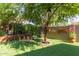 Beautiful backyard with artificial turf, decorative figures, a small bridge, and mature trees at 3823 S 101St Dr, Tolleson, AZ 85353