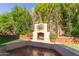 Outdoor fireplace surrounded by lush greenery, providing a cozy and inviting space for relaxation at 3823 S 101St Dr, Tolleson, AZ 85353