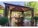 Charming outdoor dining area with gazebo, decorative fireplace, and lush green landscaping at 3823 S 101St Dr, Tolleson, AZ 85353