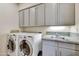 Well-equipped laundry room with white cabinets, stone countertops and modern washer/dryer at 39032 N 101St Way, Scottsdale, AZ 85262