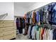 Organized walk-in closet features many hanging clothes and wooden dresser at 4647 E County Down Dr, Chandler, AZ 85249