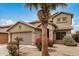 Two story home with desert landscaping, a large palm tree, and two car garage at 5220 W Desert Ln, Laveen, AZ 85339