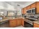 Well-lit kitchen featuring wood cabinetry, stainless steel appliances, and a mosaic backsplash at 5220 W Desert Ln, Laveen, AZ 85339