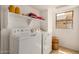 Well-lit laundry room with modern washer, dryer, and shelving at 5220 W Desert Ln, Laveen, AZ 85339