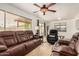 Comfortable living room with leather couches, tile flooring, and a ceiling fan at 5220 W Desert Ln, Laveen, AZ 85339