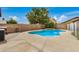 Private backyard pool with surrounding concrete patio, brick wall, and leafy trees at 5220 W Desert Ln, Laveen, AZ 85339