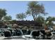Welcoming entrance to 'The Bridges at Gilbert' with a stone waterfall and lush landscaping creates a scenic first impression at 5420 S Mariposa Dr, Gilbert, AZ 85298