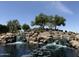 Scenic view of the The Bridges at Gilbert entrance featuring a rock waterfall and desert landscaping at 5420 S Mariposa Dr, Gilbert, AZ 85298