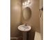 Charming half bathroom featuring a pedestal sink, round mirror, and neutral decor with decorative lighting at 7126 N 19Th Ave # 108, Phoenix, AZ 85021
