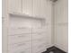Spacious walk-in closet with custom white built-in cabinets and drawers for optimal storage at 7222 E Gainey Ranch Rd # 140, Scottsdale, AZ 85258
