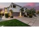 Inviting townhome featuring a two-car garage, manicured landscaping, and ambient outdoor lighting at 7222 E Gainey Ranch Rd # 140, Scottsdale, AZ 85258