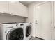 Well-equipped laundry room with white front-loading washer and dryer and ample cabinet space above at 7222 E Gainey Ranch Rd # 140, Scottsdale, AZ 85258