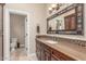 Bathroom features a decorative mirror, tile countertop, wood cabinets and view to toilet area at 8255 E Yearling Rd, Scottsdale, AZ 85255