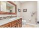 Bathroom featuring granite countertop, wood cabinets, mosaic tile backsplash, and toilet at 8255 E Yearling Rd, Scottsdale, AZ 85255