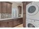 Laundry room with dark cabinets, a sink with marble countertop, and stacked washer/dryer at 8255 E Yearling Rd, Scottsdale, AZ 85255