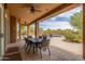 Covered outdoor patio with a dining table, ceiling fan, and views of the pool and desert landscape at 8255 E Yearling Rd, Scottsdale, AZ 85255