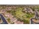 An aerial of a neighborhood with a golf course including manicured grass, sand traps and a small lake at 9702 E Naranja Ave, Mesa, AZ 85209