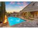 Stunning backyard oasis with a refreshing pool, ambient fire features, and mature trees at sunset at 9702 E Naranja Ave, Mesa, AZ 85209