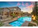 Beautiful backyard showcases a pool and spa, fire features, and an outdoor living area at sunset at 9702 E Naranja Ave, Mesa, AZ 85209