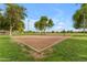 Community sand volleyball court surrounded by grass and trees, offering a fun outdoor activity at 9702 E Naranja Ave, Mesa, AZ 85209