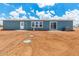 Back exterior showcasing a blue home with white trim and a spacious dirt yard under a partly cloudy sky at 10150 E Shallow Canyon Rd, San Tan Valley, AZ 85143
