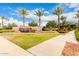 Community entrance featuring a welcoming sign, beautiful landscaping, and palm trees against a blue sky at 10545 E Texas Ave, Mesa, AZ 85212