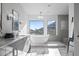 An elegant bathroom boasts a soaking tub, marble floors, and a large window overlooking the outdoors at 11446 E Sweetwater Ave, Scottsdale, AZ 85259