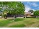 Back of house with covered patio, green grass, trees, and manicured hedges at 13015 W Blue Sky Dr, Sun City West, AZ 85375