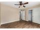 Bedroom with ceiling fan, wood floors, adjoining bathroom and closet with sliding doors at 13015 W Blue Sky Dr, Sun City West, AZ 85375
