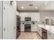 Contemporary kitchen with white cabinets, stainless steel appliances, quartz countertops, and herringbone floors at 13540 N 87Th Dr, Peoria, AZ 85381
