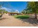 Large backyard boasts gravel landscaping, a grassy area, mature trees, and a covered patio, perfect for outdoor living at 14627 N 55Th Pl, Scottsdale, AZ 85254