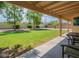 View of the well-manicured backyard featuring lush green grass, mature trees, and a covered patio at 14627 N 55Th Pl, Scottsdale, AZ 85254