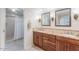 Bathroom featuring double vanity with wood cabinets, granite countertops, tile floors, and a shower at 14627 N 55Th Pl, Scottsdale, AZ 85254