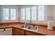 A kitchen sink features double basin, faucet and wooden cabinets, set against a backdrop of shuttered windows at 14627 N 55Th Pl, Scottsdale, AZ 85254