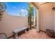 Charming patio space with tiled flooring, a stone bench, and a view of lush greenery under a sunny sky at 14627 N 55Th Pl, Scottsdale, AZ 85254