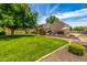 Spacious backyard with lush green lawn, mature shade trees, and a charming home in the background at 198 N Pecan Ct, Gilbert, AZ 85234