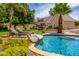 Inviting backyard oasis with a sparkling pool, comfortable lounge chairs, and lush tropical landscaping at 198 N Pecan Ct, Gilbert, AZ 85234