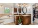 Bright bathroom featuring a soaking tub with travertine tile and double vanity sinks at 198 N Pecan Ct, Gilbert, AZ 85234