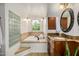 This bathroom features a soaking tub with travertine tile and a vanity with a decorative mirror at 198 N Pecan Ct, Gilbert, AZ 85234