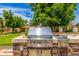 Close up of a stainless steel grill, set in a stone outdoor kitchen beneath a shady tree at 198 N Pecan Ct, Gilbert, AZ 85234