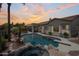 Stunning backyard pool and spa with palm trees, stone accents, and an outdoor dining area at sunset at 2105 E San Carlos Pl, Chandler, AZ 85249