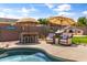 Backyard poolside featuring a built-in bar, comfortable lounge chairs, outdoor fireplace, and lush landscaping for outdoor entertaining at 2105 E San Carlos Pl, Chandler, AZ 85249