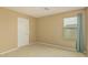 Empty bedroom with tan walls, carpet and a window with curtains at 21610 N Bradford Dr, Maricopa, AZ 85138